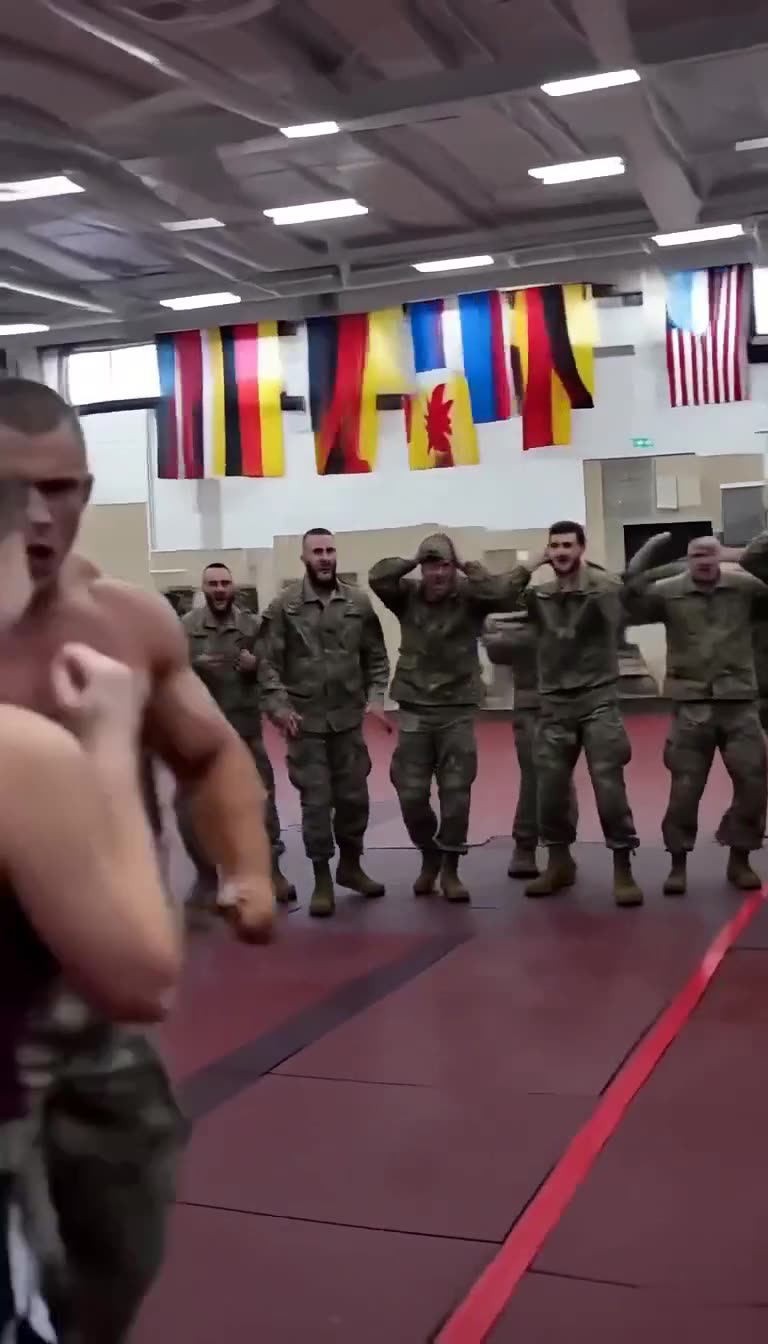 A row of uniformed soldiers erupts in cheers and grabs their heads in disbelief.