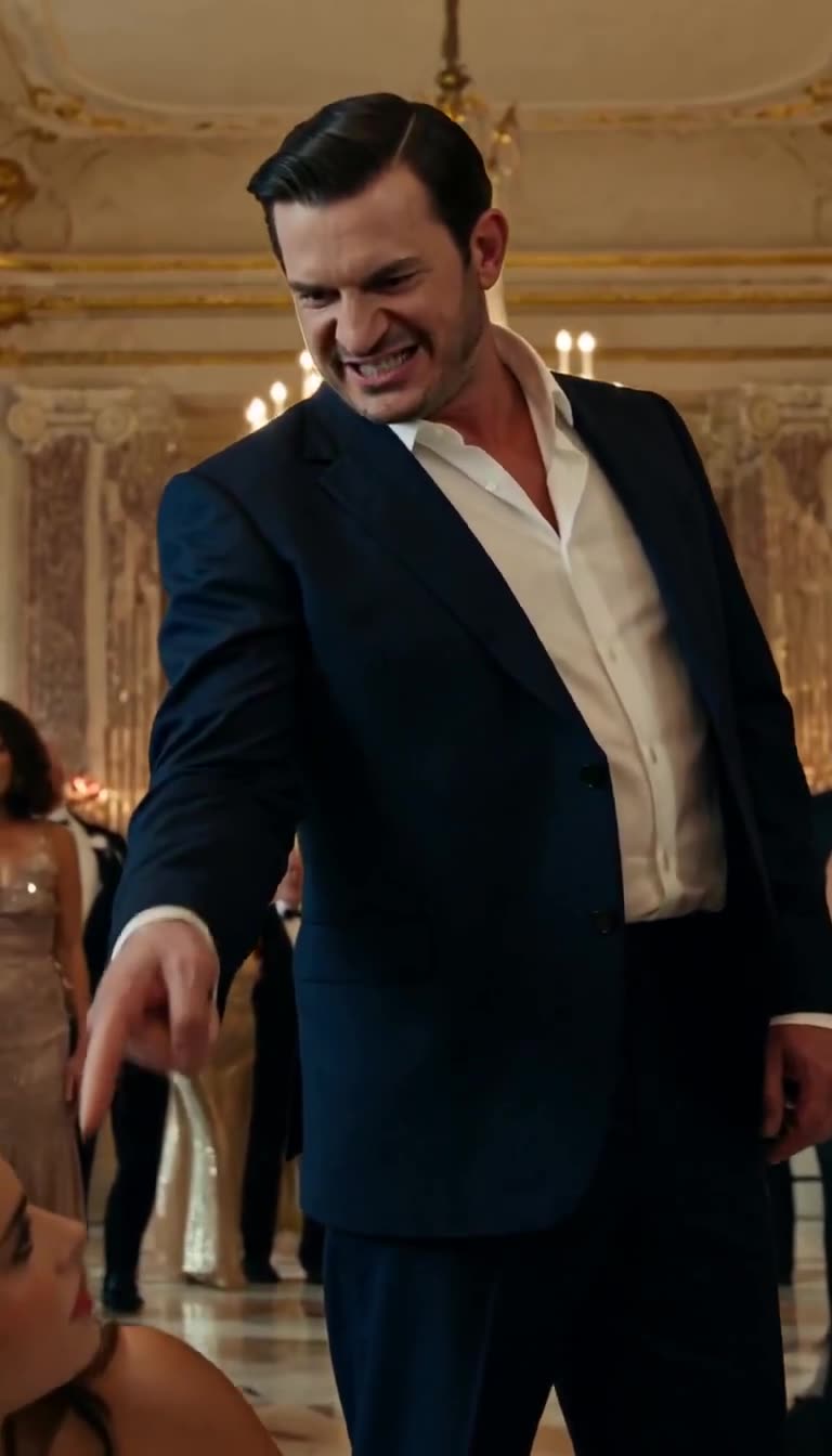 Marcus sneers in rage and points downward at Elena before gasping gala attendees.