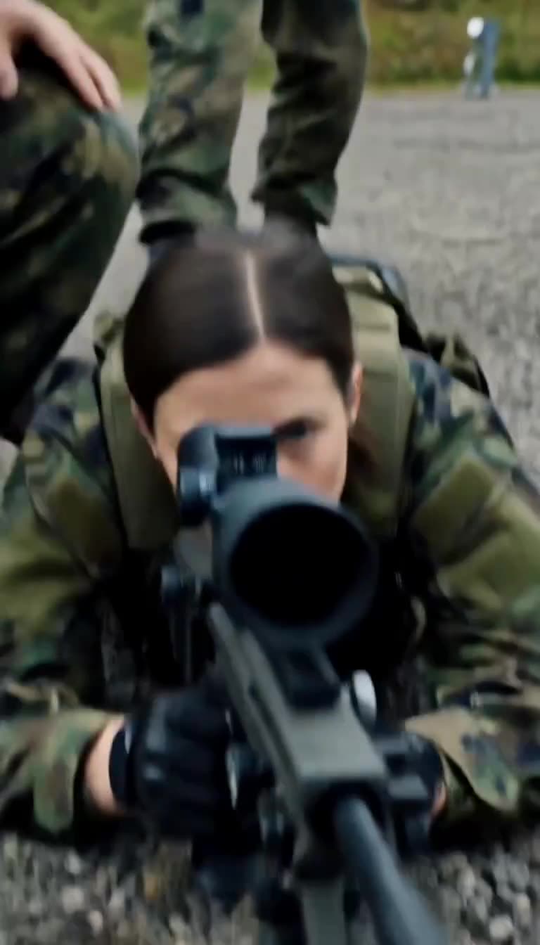 Scharfschützin Nora zielt im Liegen hochkonzentriert durch das Visier ihres Gewehrs.