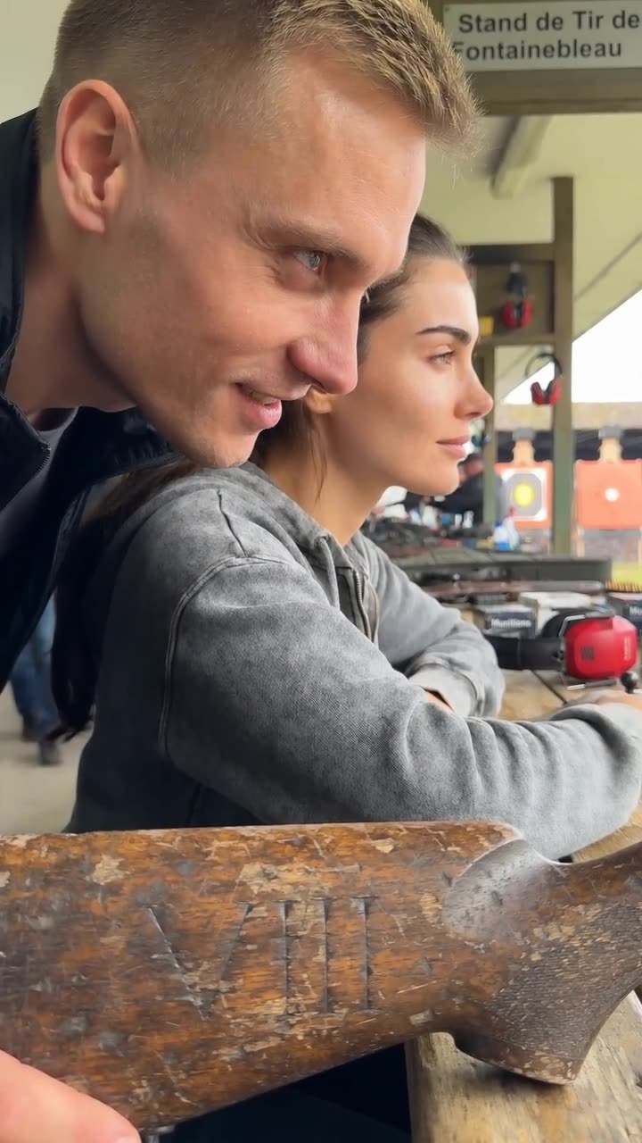 Camille maintaining steady forward focus as Maxime leans over her shoulder to mock her equipment