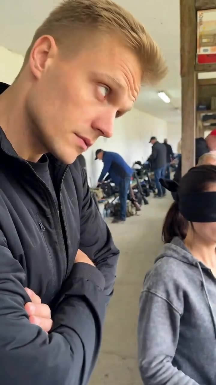 Maxime crosses his arms with a skeptical smirk while observing the blindfolded wager.