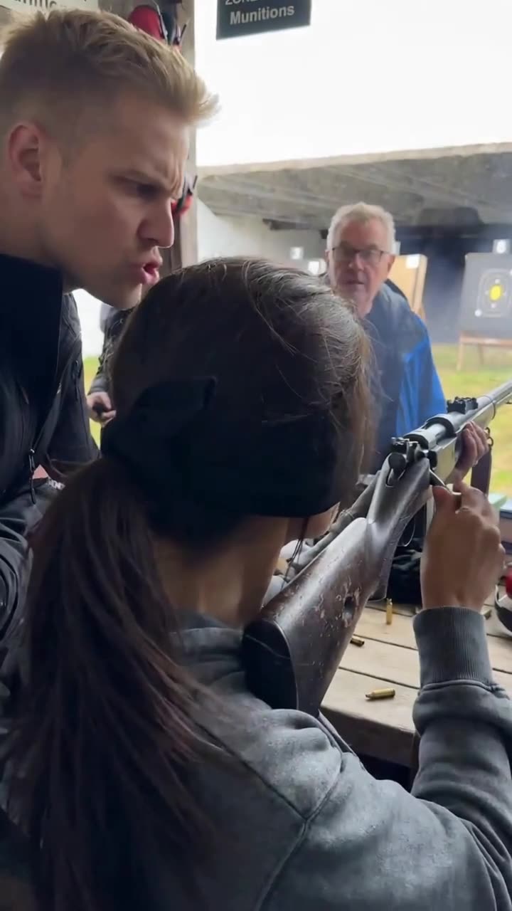 Maxime sneering and shouting tensely beside Camille as she cycles the rifle bolt