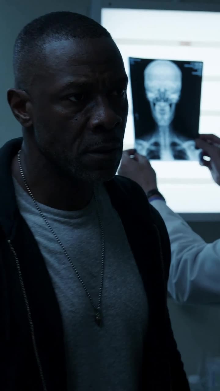 Close-up of Marcus clenching his jaw as he stares intensely at the fractured scan.