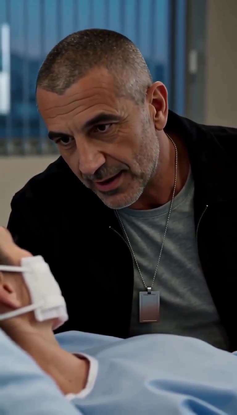 Daniel leaning down to speak gently with his injured daughter in a hospital bed