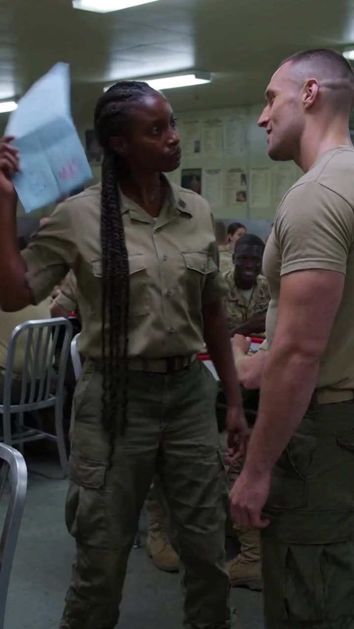 Maya raises a blue paper form with a red official stamp to shut down Derek's taunt.