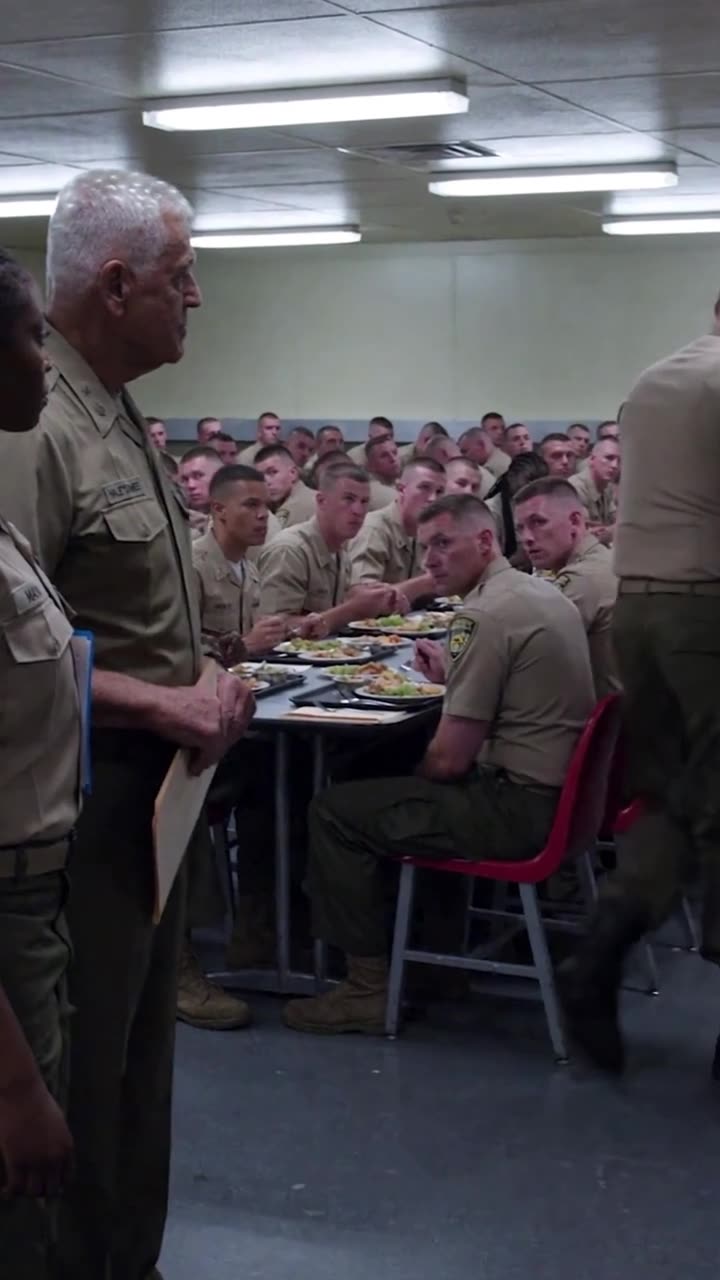 Recruits watch in stunned silence as Derek is escorted out of the crowded dining hall.