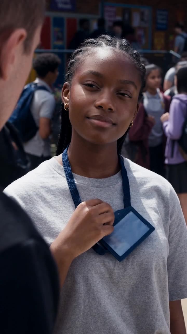 Maya reaches for her lanyard card with a confident, knowing gaze.