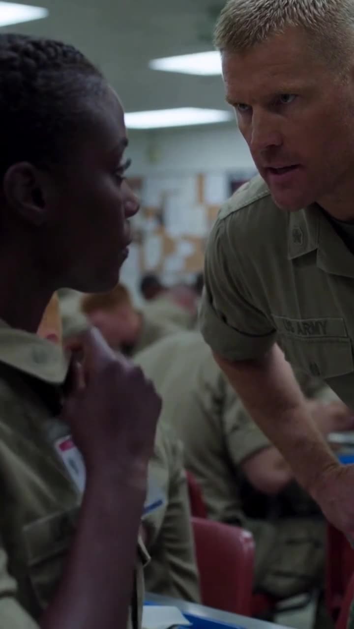 Close-up of the instructor glaring fiercely while the female soldier maintains eye contact