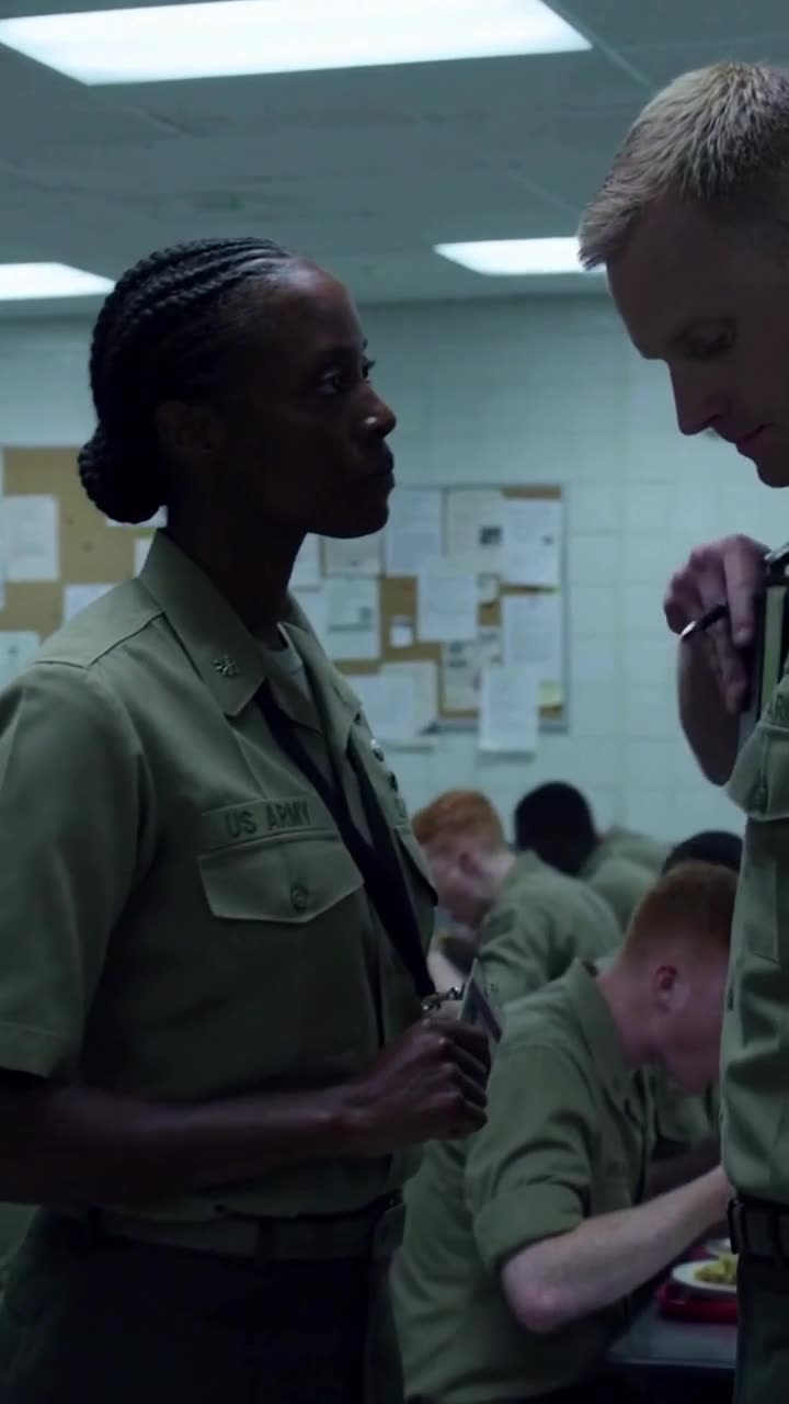 The female officer rises to her feet, locking eyes with Miller as she presents her military identification.