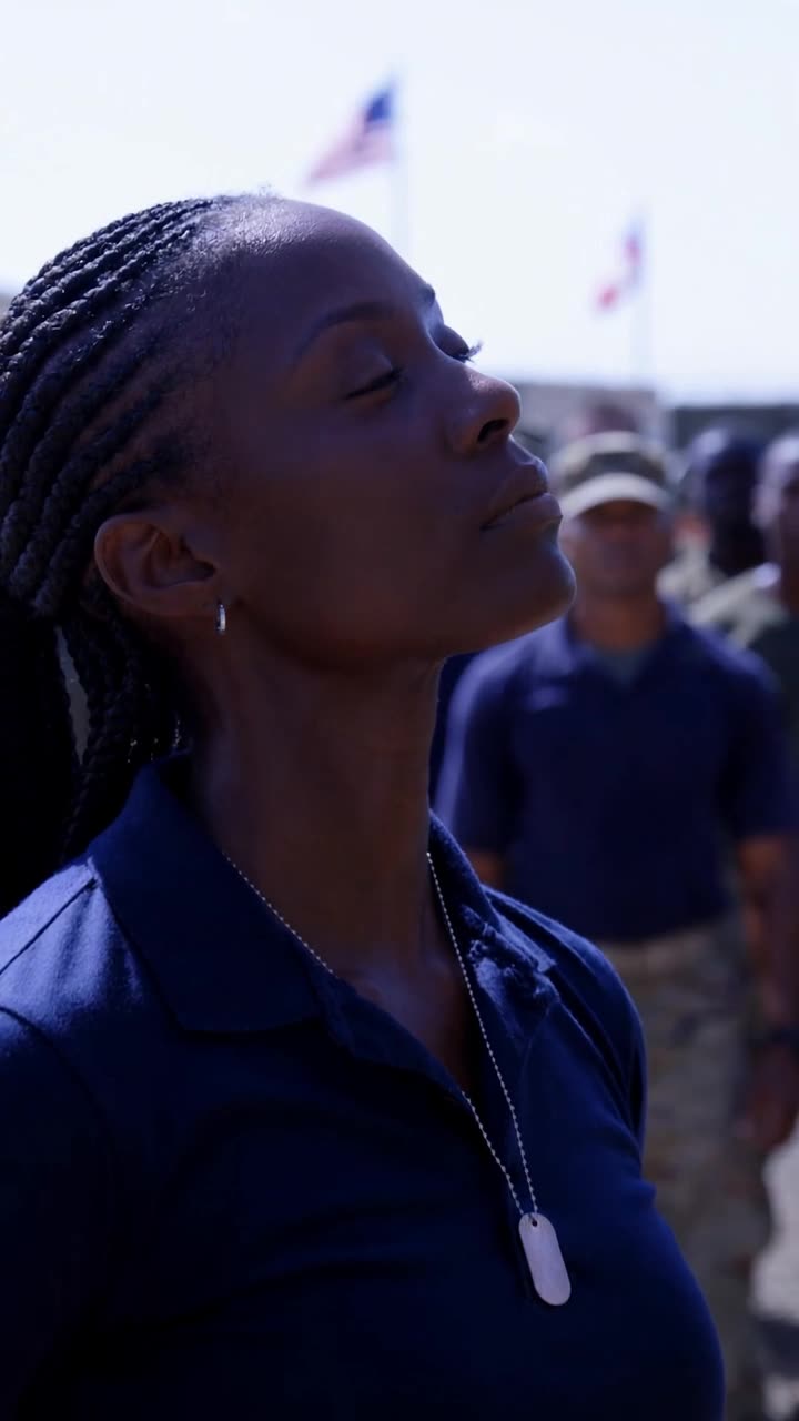 Maya tilts her chin upward calmly as a silver steel tag catches the midday sun.