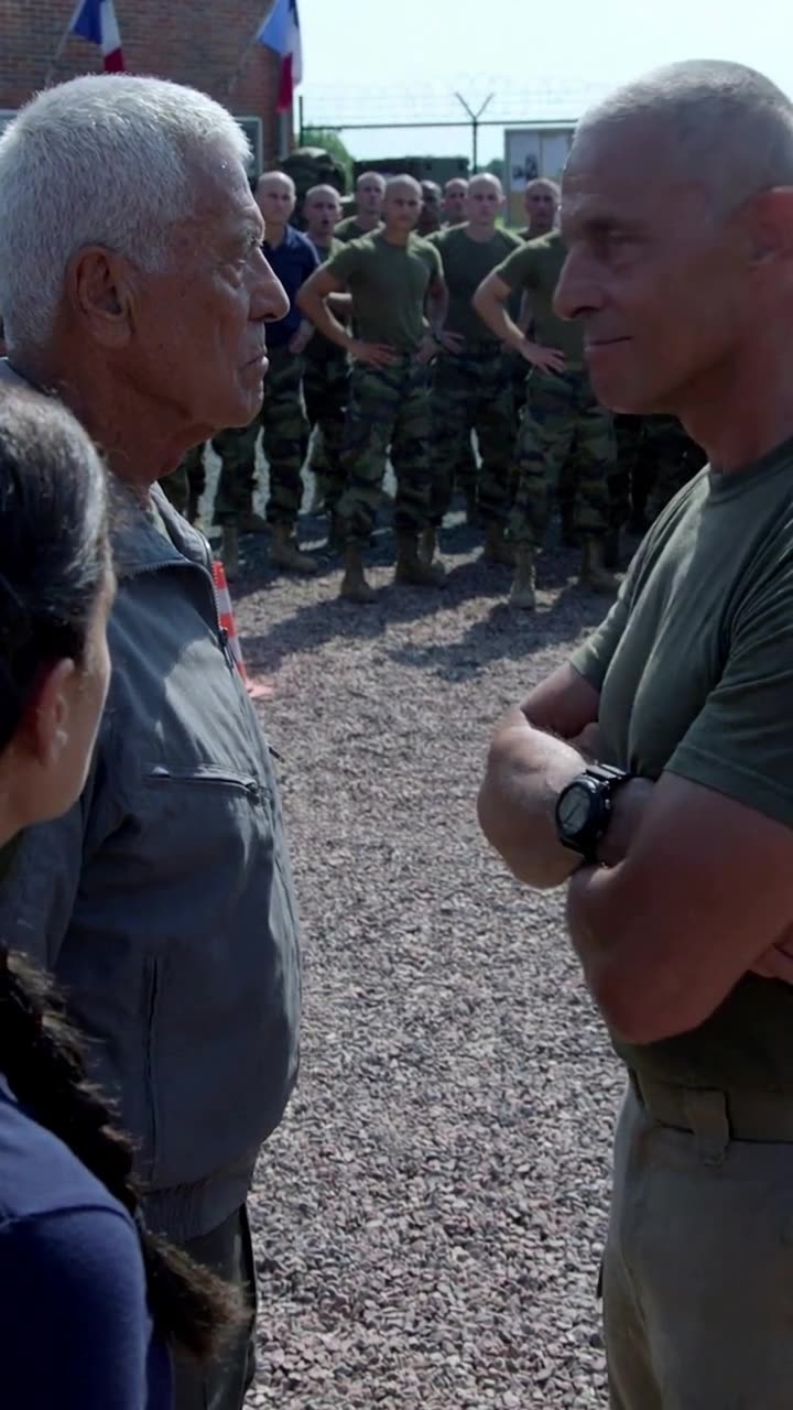 Sergeant Julien crosses his arms with a mocking smirk while confronting Pierre before the recruits.
