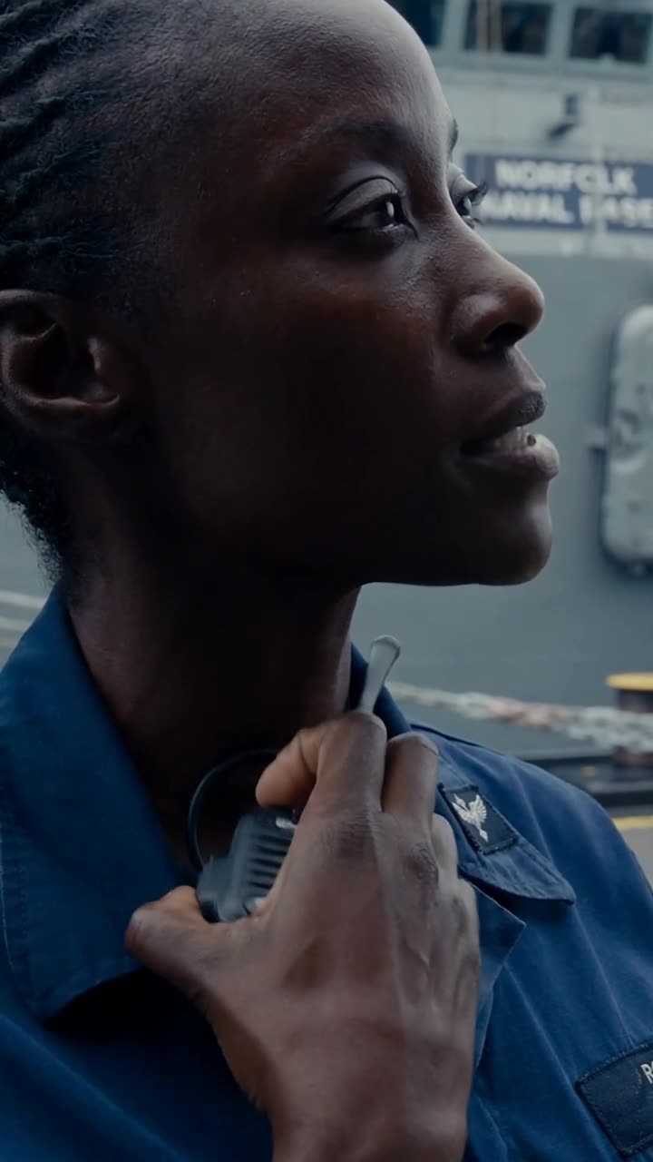 Maya reaching into her dark blue collar to reveal a concealed black transponder