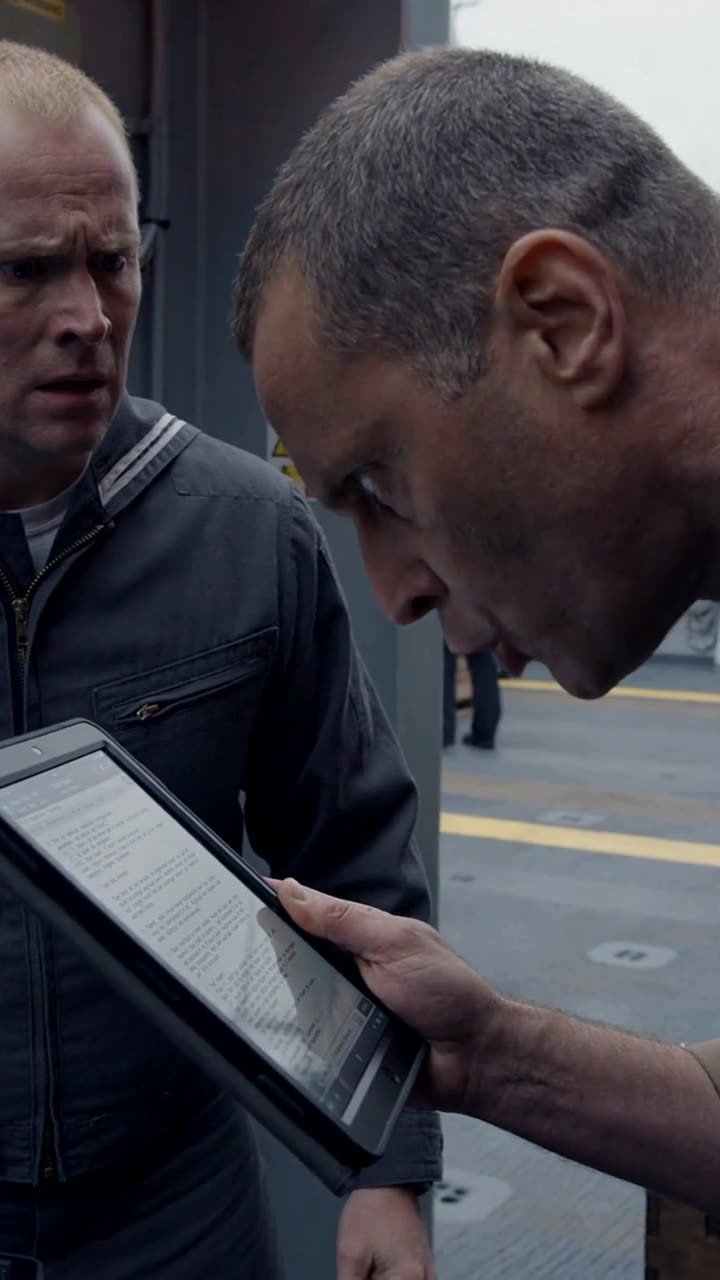 Robert staring intensely at the classified digital order on the tablet