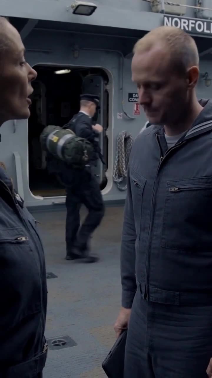Naval crew members confer hurriedly in the ship doorway as security alerts escalate