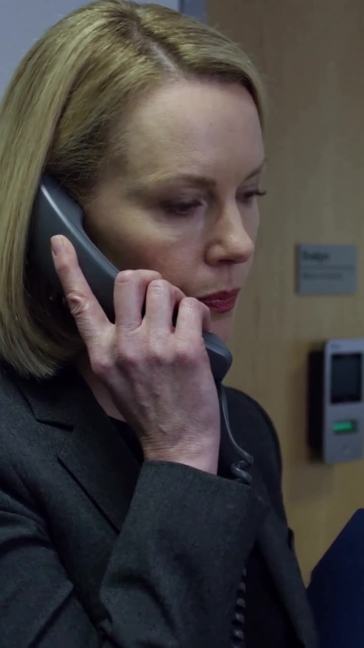 Close-up of Evelyn speaking into the receiver with a stern and decisive expression.
