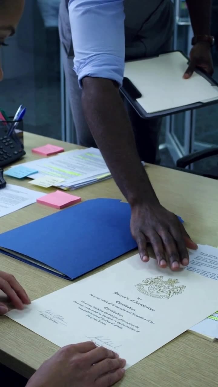 A close-up of a hand placing a patent document with a gold embossed seal on a desk
