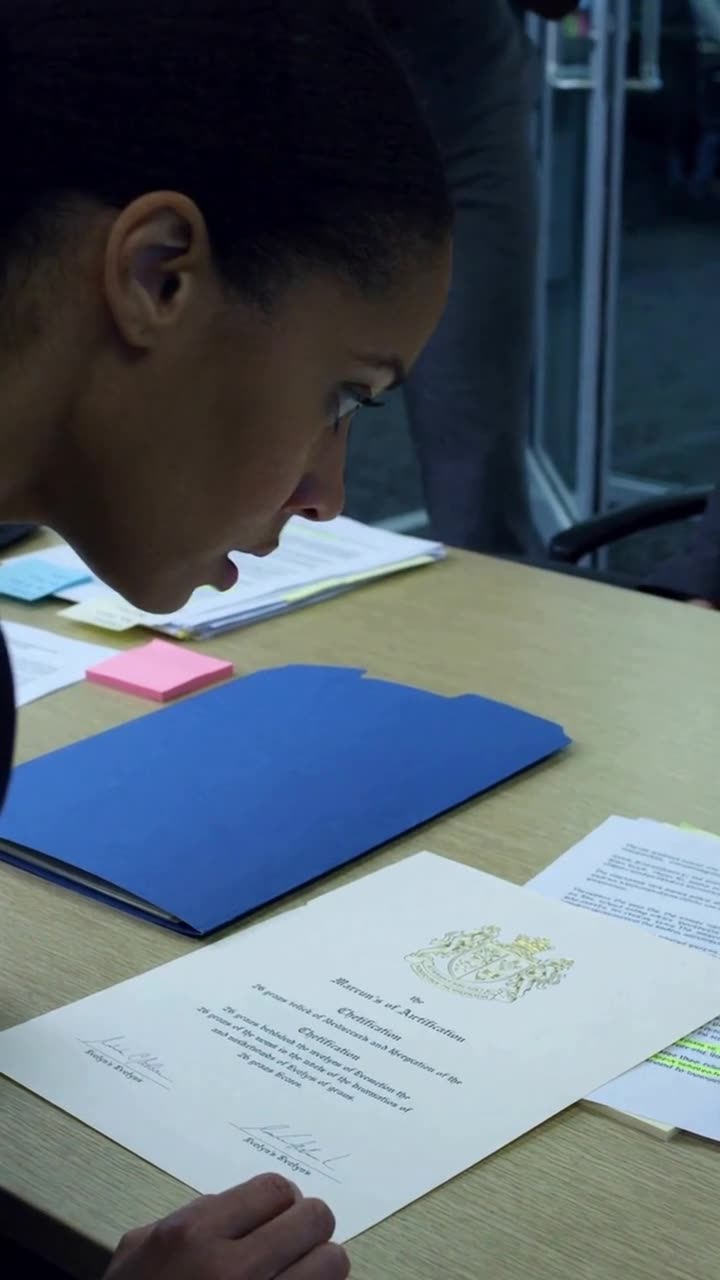 Chloe leaning forward in stunned silence as she reads the verified patent certificate