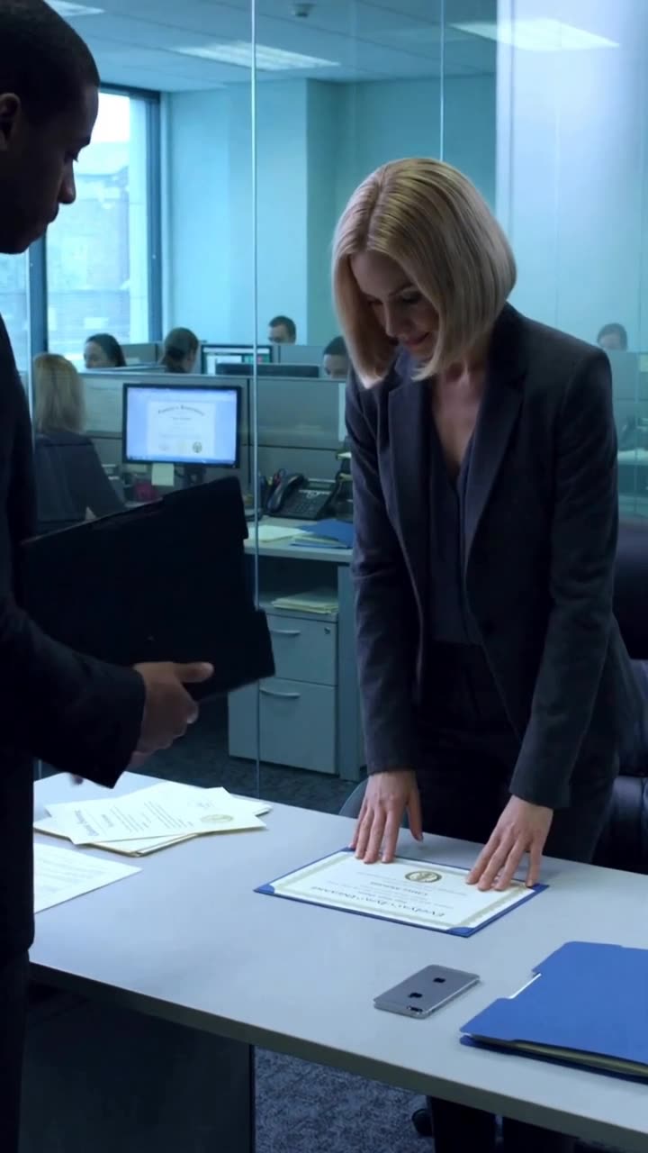 Evelyn leans forward placing both hands on the verified certificate with an approving nod.