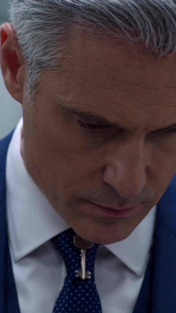 Close-up of Richard staring intently at the antique key pendant around Lucas's neck.