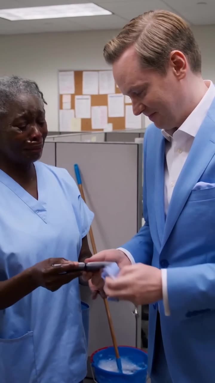 Julian gently hands the wiped phone back to a tearful Martha in the office corridor.