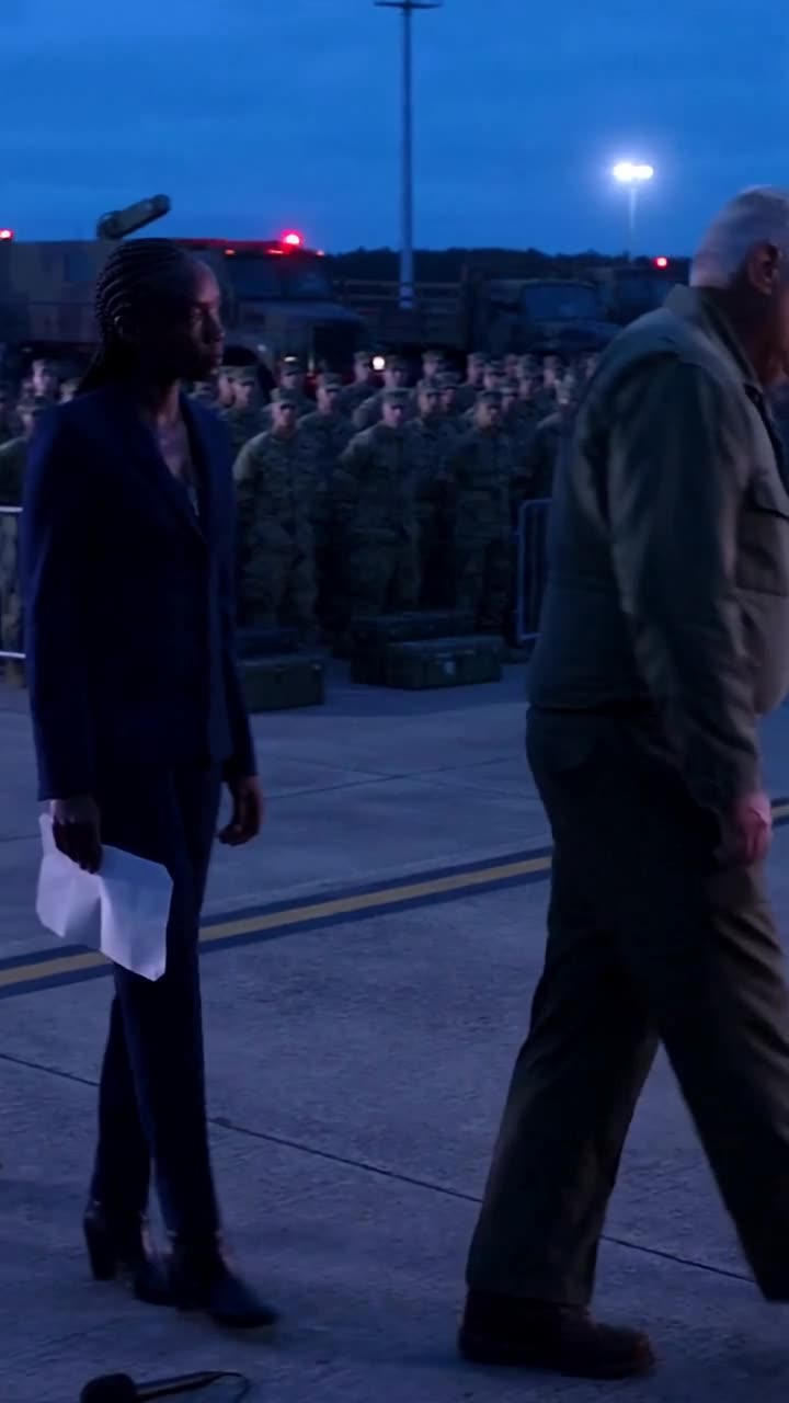 Thomas retreats across the flight line as Maya watches him leave before ranks of gathered troops.