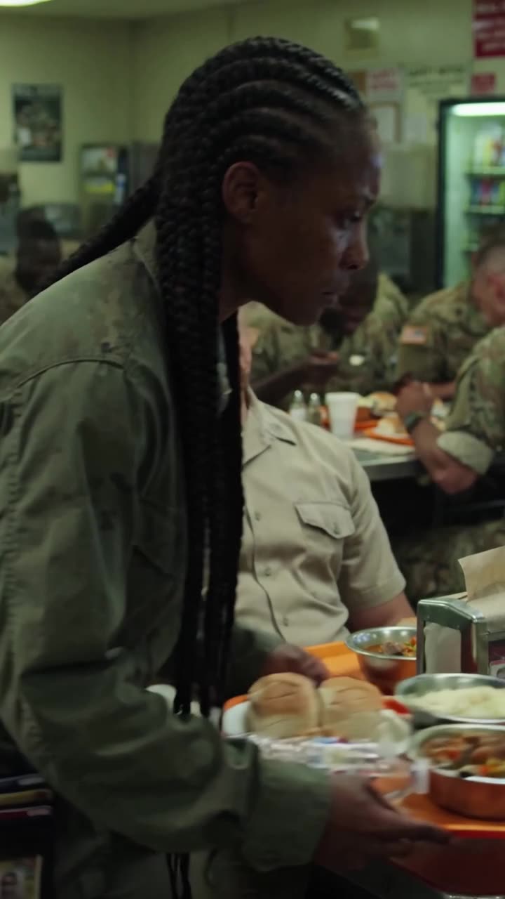 Maya steps forward firmly with the meal tray, confronting Brad as tension peaks in the mess hall.