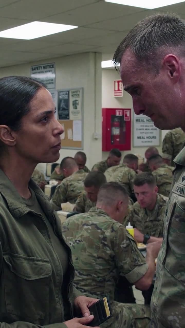 Captain Maya holds up her military badge and confronts the trembling soldier with a cold, unwavering expression.