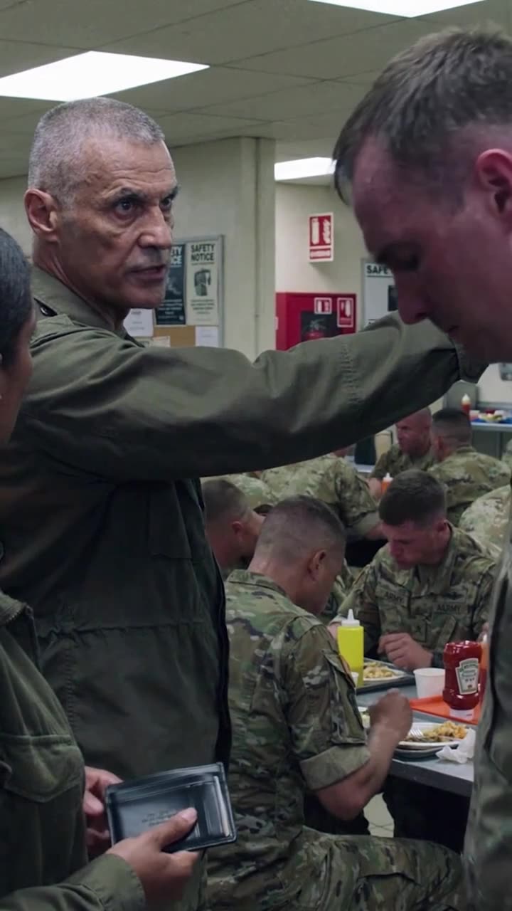 Commander Frank sternly points toward the kitchen doorway while ordering Brad to report for mess cleaning