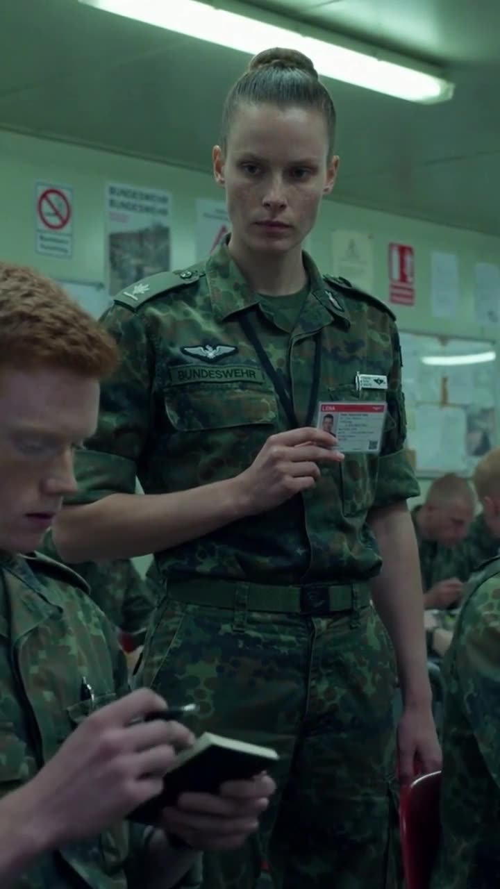 Elena steht aufrecht in Flecktarn-Uniform und zeigt ruhig ihren offiziellen Dienstausweis vor.
