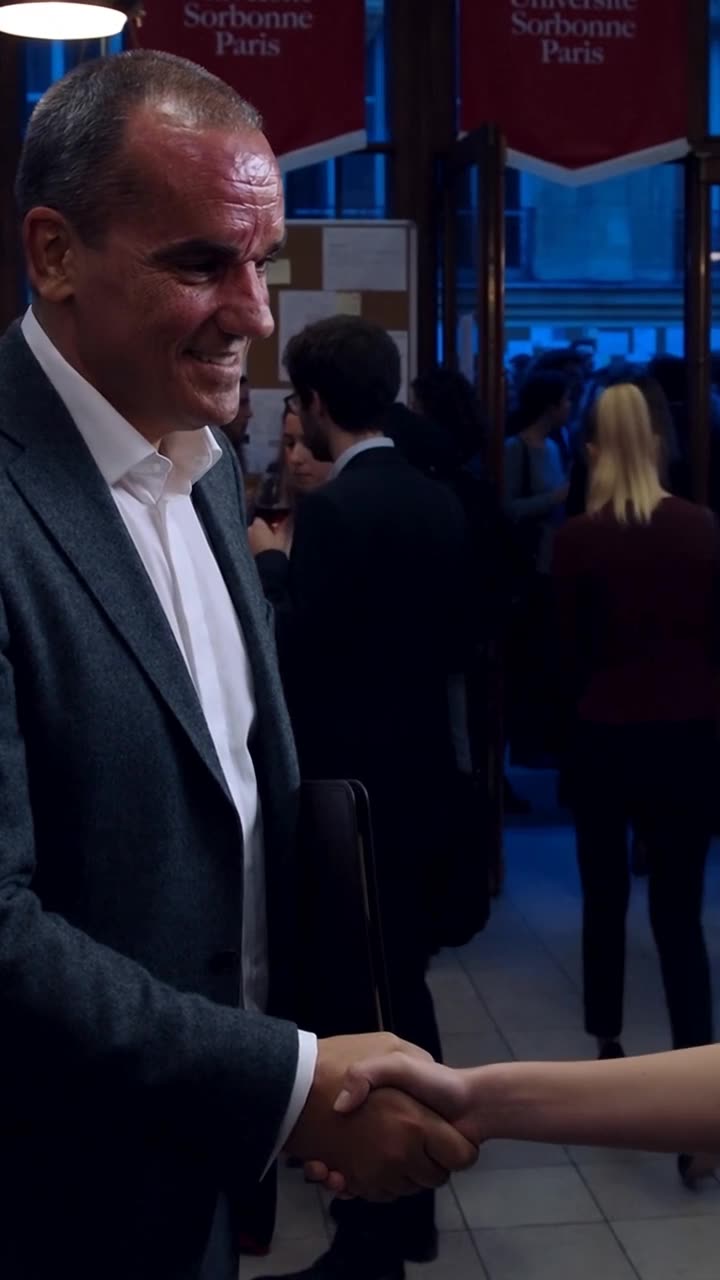 Antoine shakes Camille's hand in congratulation while Chloé walks away in defeat toward the exit