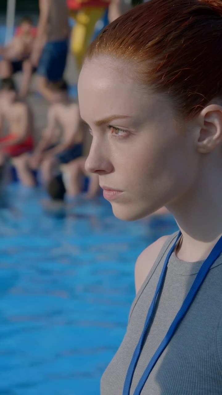 Camille watches with a focused, resolute expression as she steps forward toward the poolside altercation.