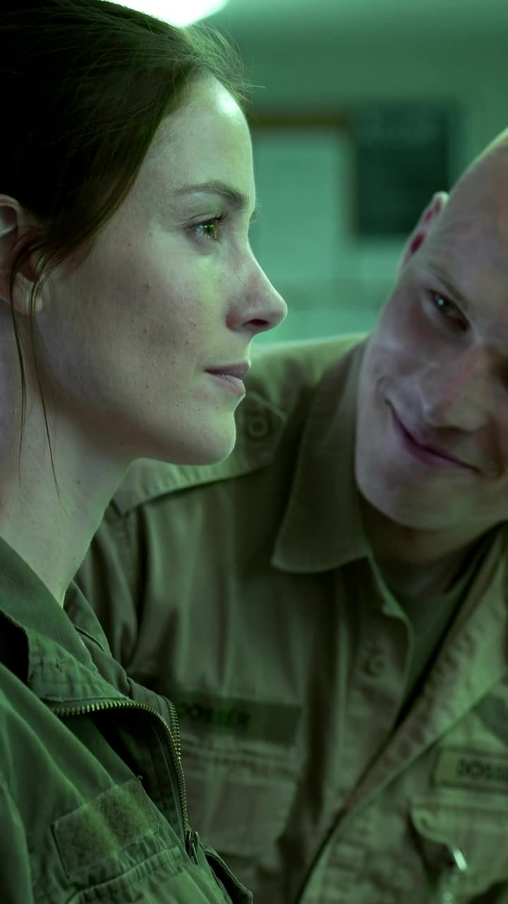 A tense close-up shows Léa holding her ground stoically while Julien sneers into her personal space.