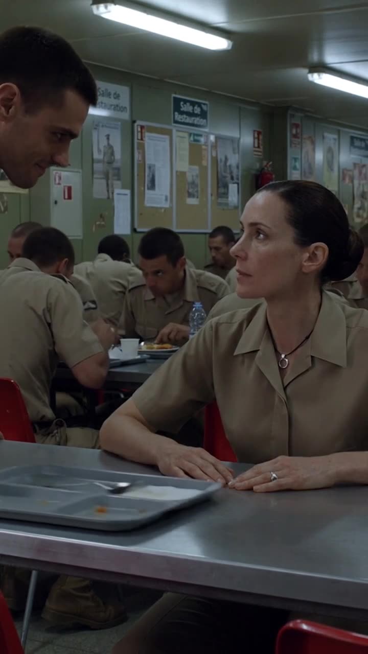 The female officer looks calmly across the table as the smug officer taunts her.