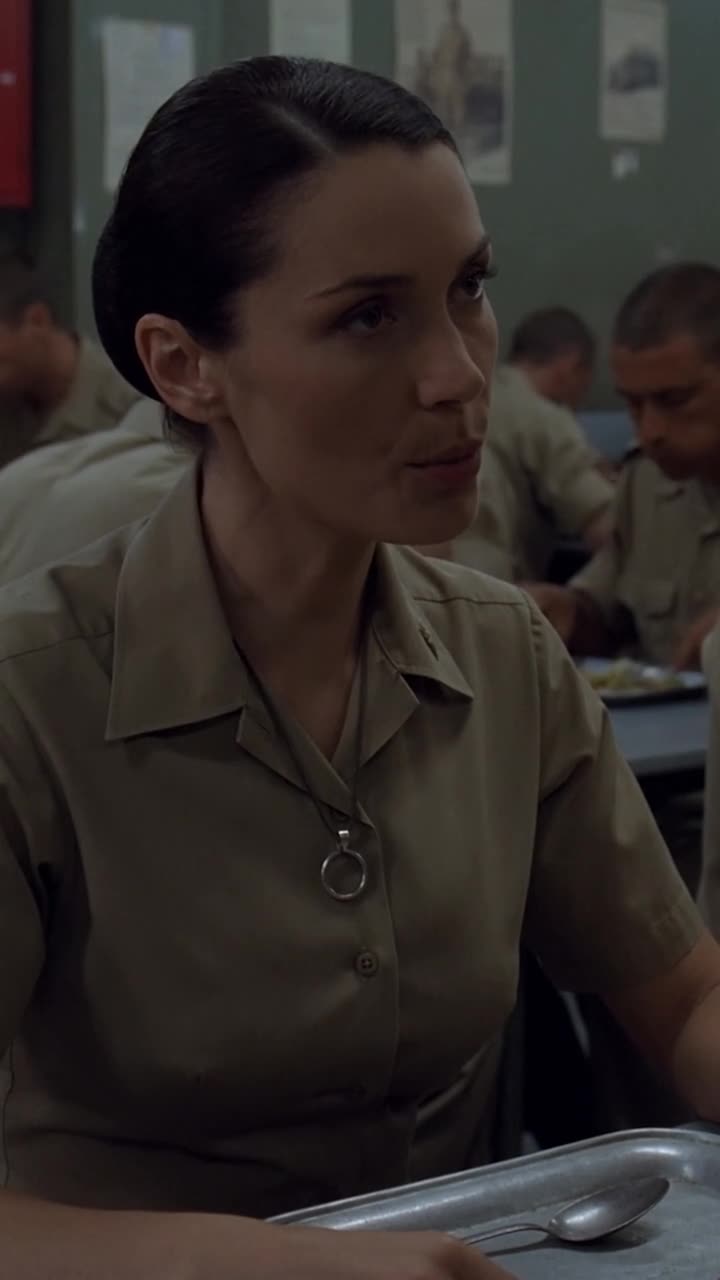 Claire looks up calmly with the insignia ring displayed against her uniform shirt.