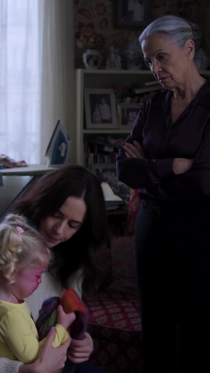Monique crosses her arms and glares down coldly at Camille and Léa