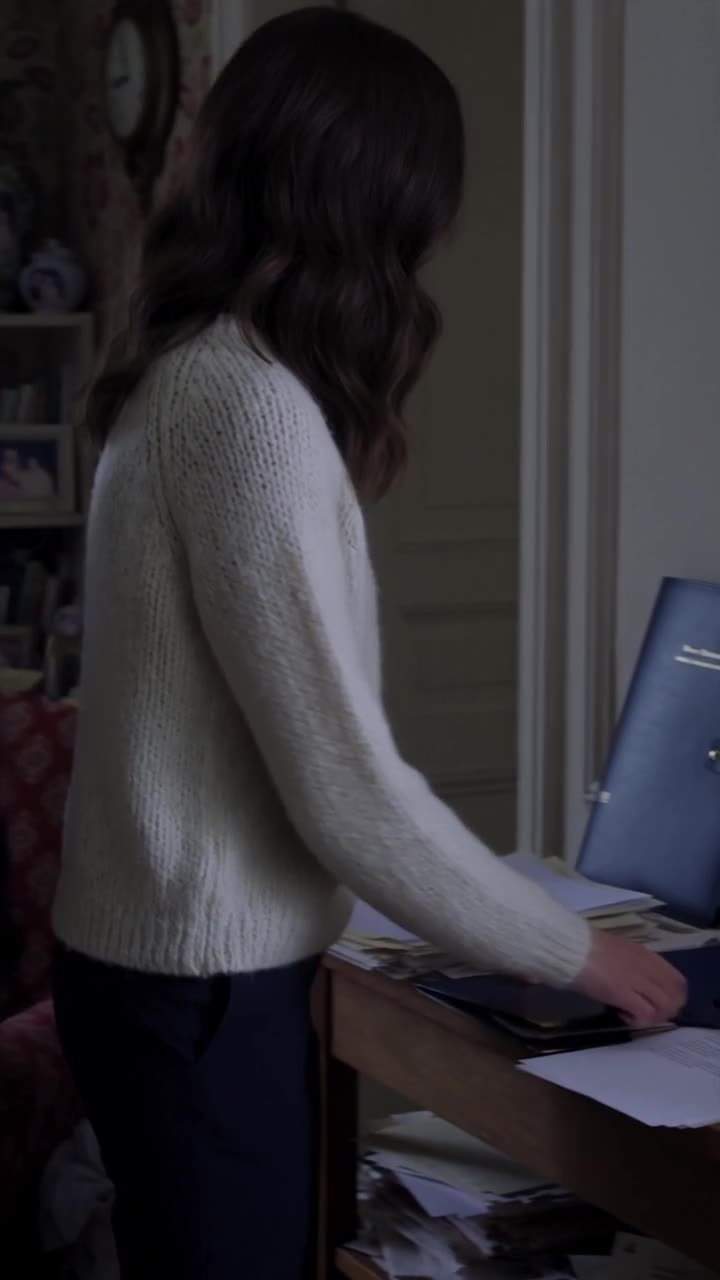 Camille walks toward the side table to retrieve the blue leather folder containing the property deed.
