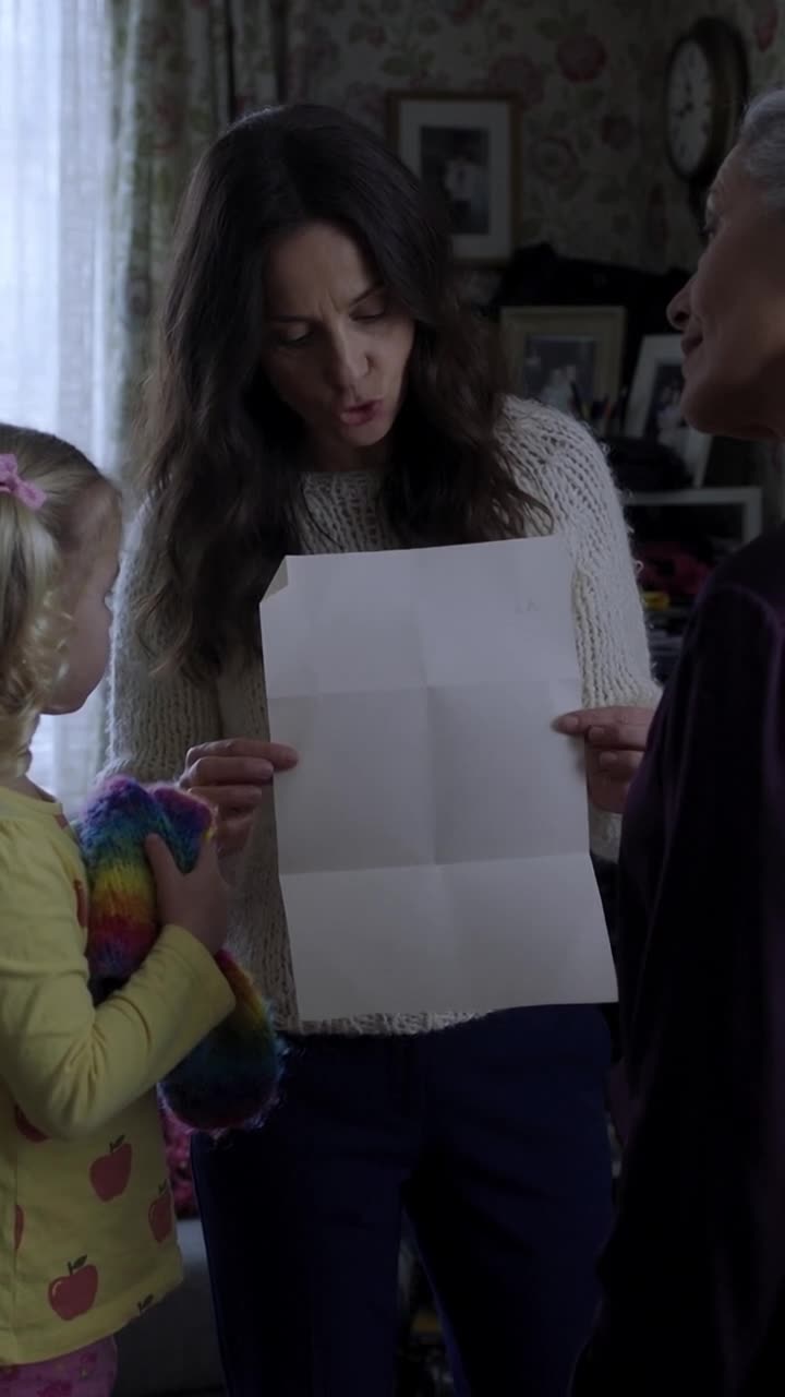 Camille unfolds the property deed squarely in front of her chest to confront Monique.