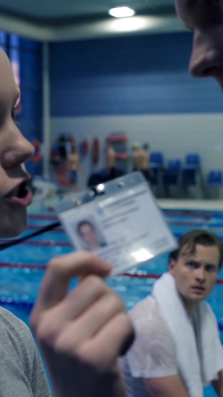 Der laminierte Ausweis des Landesschwimmverbands spiegelt sich im grellen Flutlicht der Schwimmhalle.