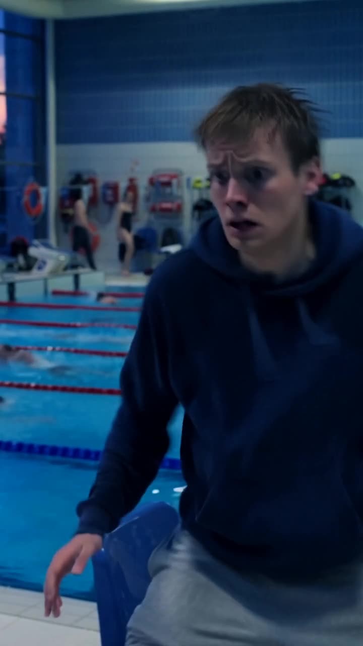 Lukas weicht mit panischem Gesichtsausdruck am Beckenrand der Schwimmhalle zurück