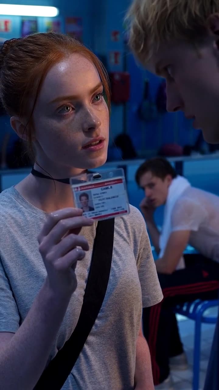 Camille holding up an official security ID badge to Maxime