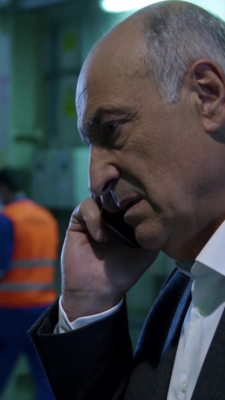 Philippe listens to his smartphone in disbelief as his confident smirk turns into a tense frown.