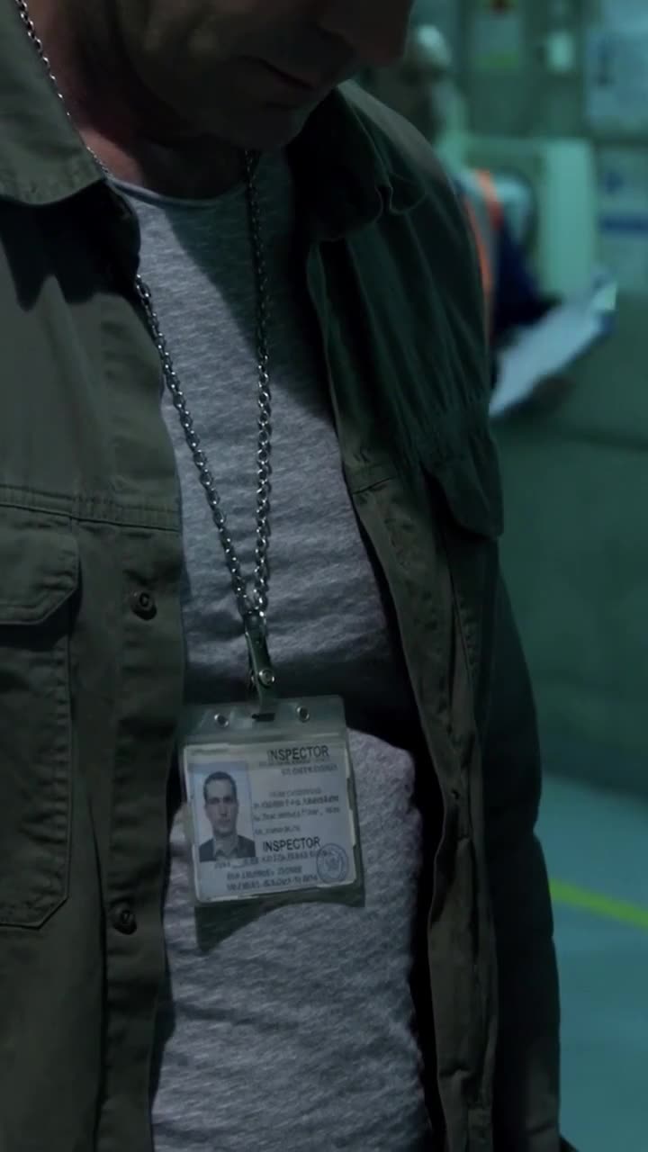 Close-up of the unkempt visitor revealing an official Supreme Inspector identity badge around his neck