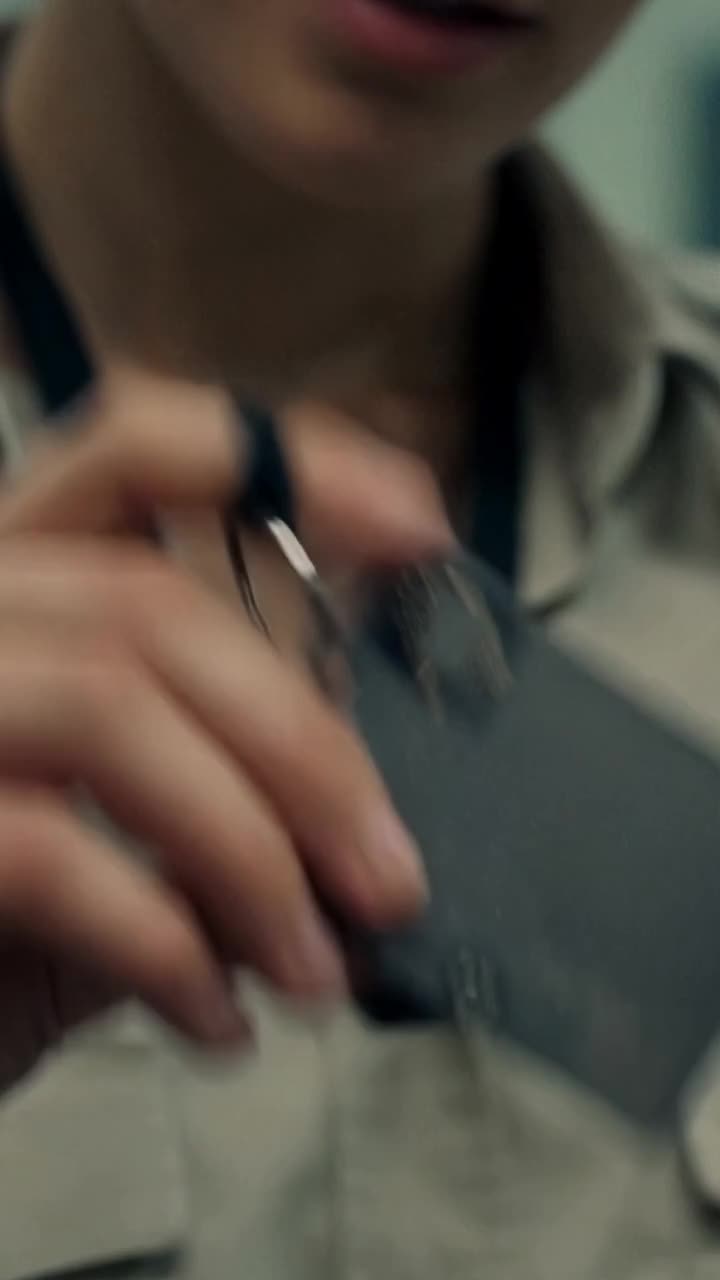 Lena zieht eine matte schwarze Titankarte an einer Kordel unter ihrem Kragen hervor