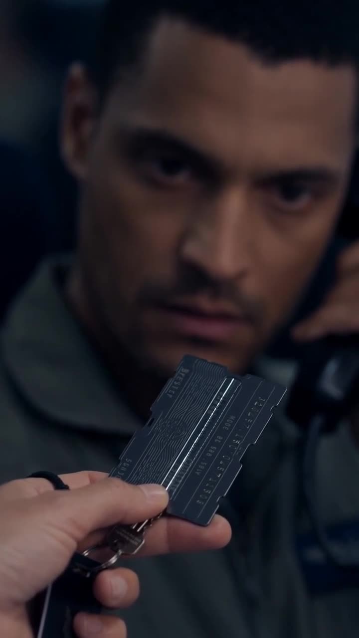 An officer examining the black tactical clearance keycard in shock