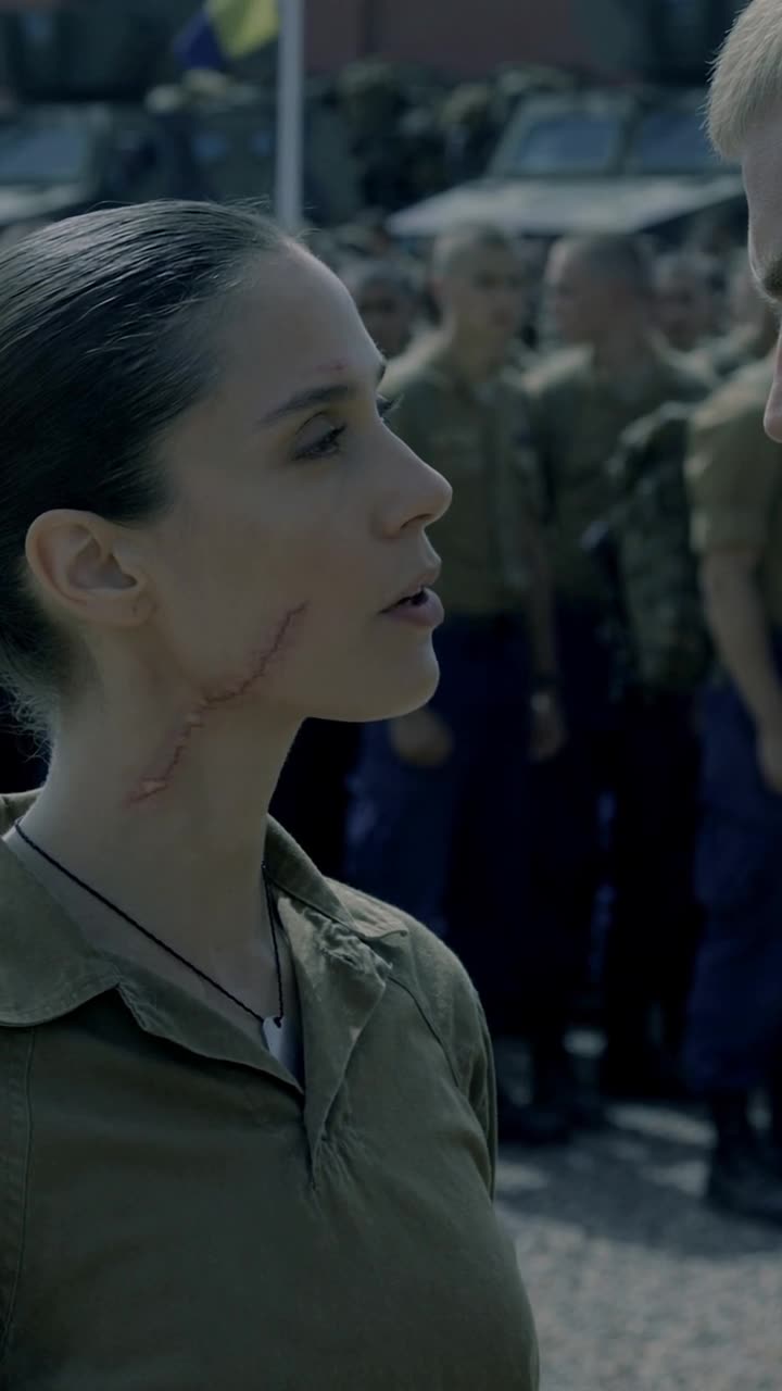 Camille lifts her chin calmly revealing her hidden neck cord and command insignia