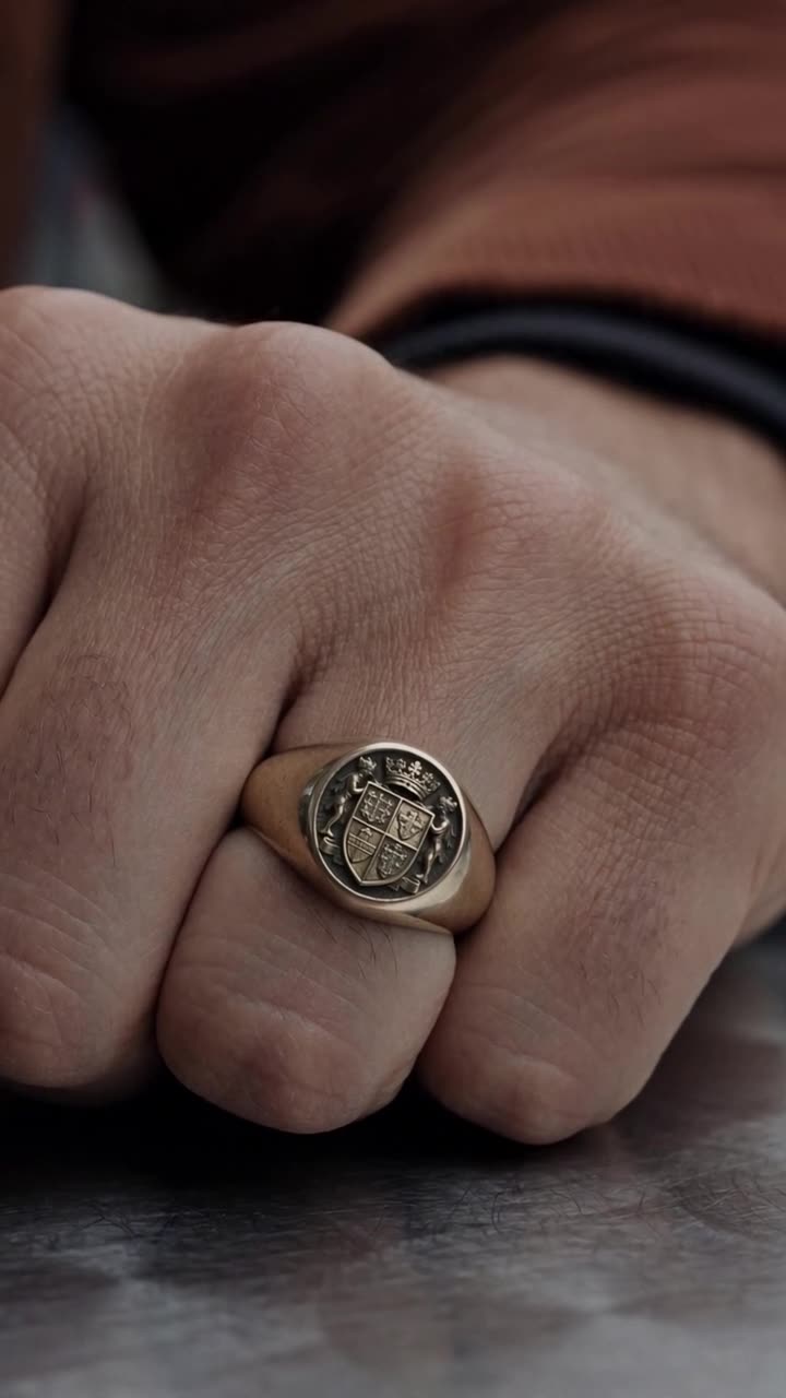 Makroaufnahme des massiven Siegelrings mit graviertem Wappen auf Maximilians Hand.