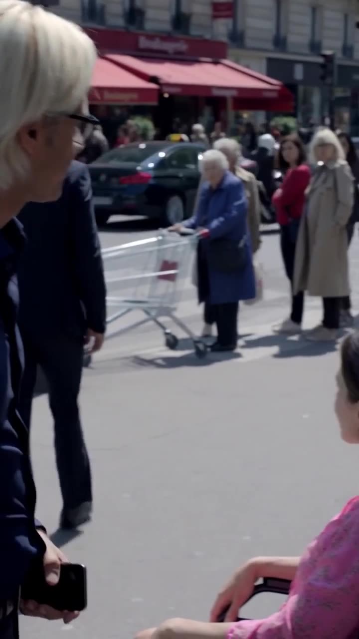 A gentleman standing beside a woman in a wheelchair on a busy city street