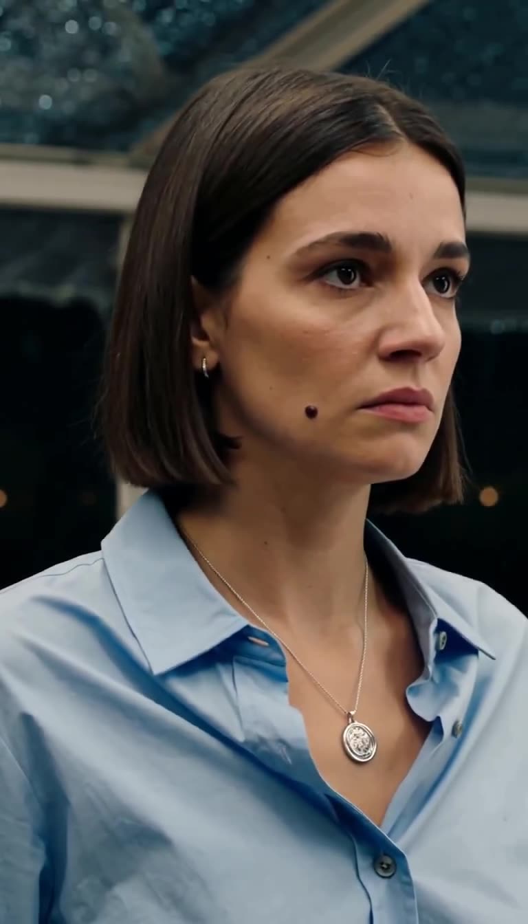A close-up of Camille revealing the round silver family seal pendant hanging from her neck.